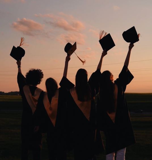 Graduate holding cap up in celebration